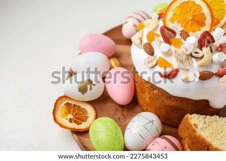 Traditional Easter cake with dried fruits and painted eggs on white table, closeup. Space for text