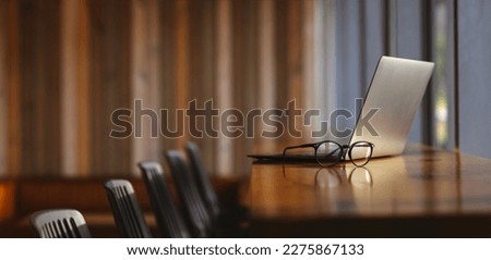 Modern and empty office desk with a laptop, computer, and eyeglasses. Still life shot of a professional working space in a coworking office. Royalty-Free Stock Photo #2275867133
