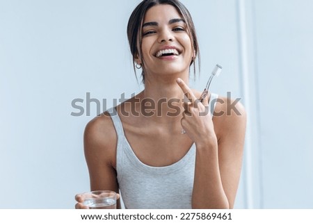 Shot of pretty young woman brushing her teeth while looking at camera in the bathroom at home. Royalty-Free Stock Photo #2275869461