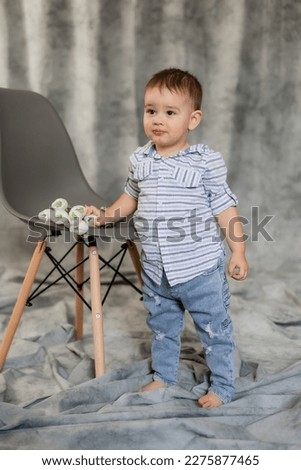 cute baby boy in jeans and shirt on a gray background in the studio