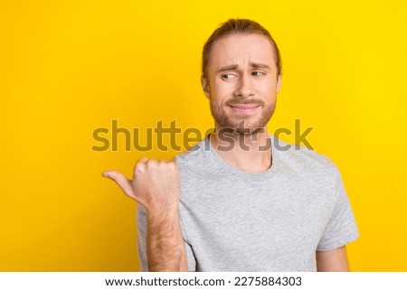 Photo of minded man wear grey clothes arm presenting empty space novelty feedback isolated on yellow color background