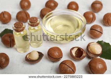 Delicious organic Macadamia nuts and natural oil on white textured table, closeup Royalty-Free Stock Photo #2275885223