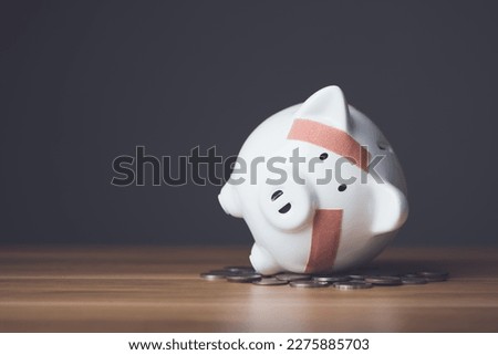 Financial problem, Bankrupt or fail in business concept. White piggy bank with plastic adhesive bandages on wooden desk with dark copy space wall background. Fail, Bankrupt or unsuccessful idea. Royalty-Free Stock Photo #2275885703