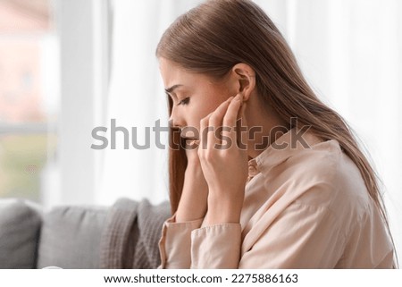 Young woman with ear plugs suffering from loud noise at home, closeup Royalty-Free Stock Photo #2275886163