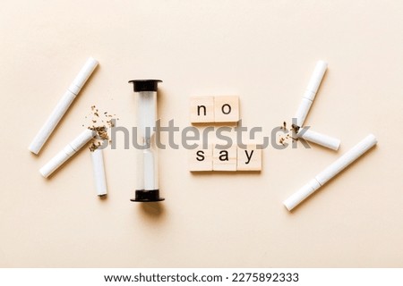 Cigarette And Wooden Blocks, Broken cigarette on table background with hourglass, No Tobacco Day with hourglass, clock health concept. time to quit smoking.