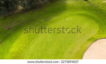 Aerial view of an empty golf course with green hills and sand bunkers. The sports club is empty and nobody is playing. Sports concept.