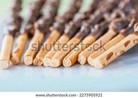 Group of chocolate covered pretzel sticks on a white plate.