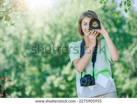Woman is taking a picture with a camera in the park. Royalty-Free Stock Photo #2275905955