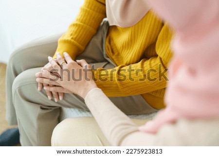 Asian muslim women encouraging her friend who have a critical problem. Woman touching and holding her friend's hands with empathy. Royalty-Free Stock Photo #2275923813