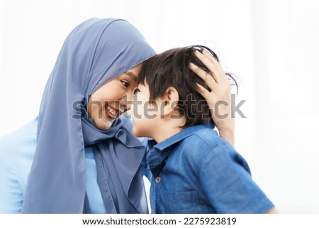 Happy cheerful Asian muslim family stay together in living room in weekend, Beautiful Asian woman muslim and lovely little boy portrait and looking at camera.