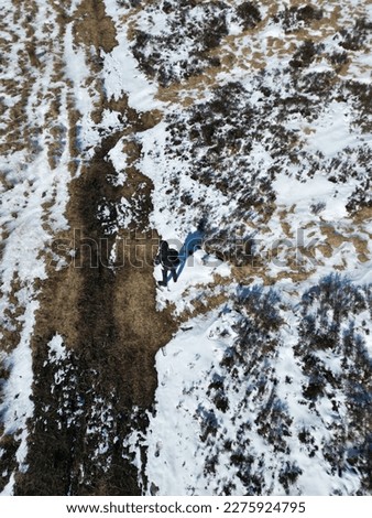 Aerial view of snow covered fields with a single person standing below. 