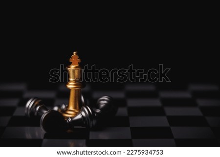 Gold king chess standing in center surround by fallen silver king chess, knight and other pieces in black background. Winner in business competition, marketing strategies and leadership concept. Royalty-Free Stock Photo #2275934753