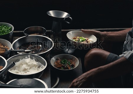 Preparing of Thai local food, dried rice porridge, in the floating boat at Thailand traditional floating market. Senior male local chef cooking dish for his customer. Royalty-Free Stock Photo #2275934755