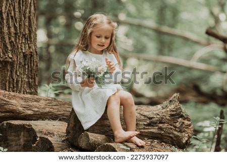 a cute little girl with long hair in a white cotton dress runs barefoot in the woods in summer. The concept of Earth Day. Save the planet