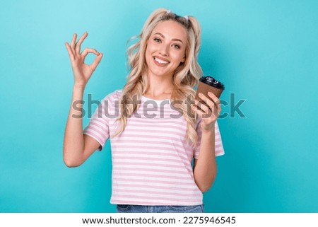Portrait of cute cheerful lady hold coffee cup demonstrate okey symbol isolated on turquoise color background