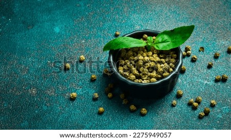 Fragrant green pepper peas in a bowl. Spices and condiments. Top view. On a green background.