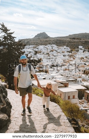 Father and child walking in Lindos city family travel in Rhodes island, Greece man with daughter together sightseeing landmarks summer vacations lifestyle  Royalty-Free Stock Photo #2275977933