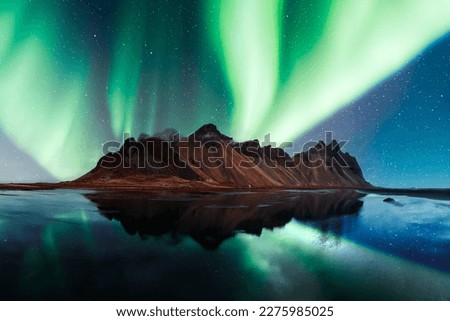 Aurora borealis Northern lights over famous Stokksnes mountains on Vestrahorn cape. Reflection in the clear water on the epic skies background, Iceland. Landscape photography Royalty-Free Stock Photo #2275985025