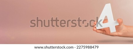 number four in hand. Hand holding white number 4 on red background with copy space. Concept with number four. Birthday 4 years, fourth grade, four day work week Royalty-Free Stock Photo #2275988479