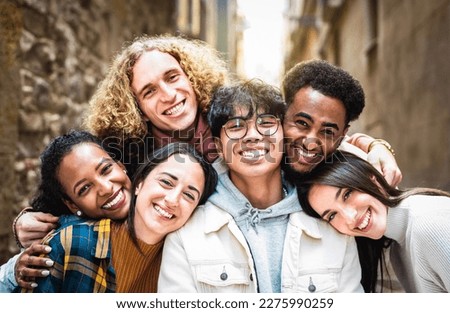 Multi racial guys and girls taking selfie outdoors with backlight - Happy life style friendship concept on young multiracial best friends having fun day together in Barcelona city - Warm vivid filter Royalty-Free Stock Photo #2275990259