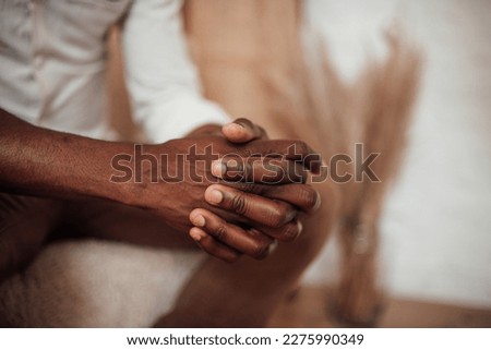 Candid millennial authentic diverse portrait of african american man relax time at apartment in neutrals tones colors interior. Domestic life multi ethnic male sitting at cozy home in day light Royalty-Free Stock Photo #2275990349