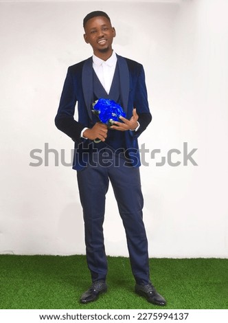 African black man wearing blue suit smiling happy looking at the camera holding blue flower