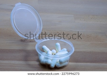 Packaging of medical pills in a plastic container on a wooden table.