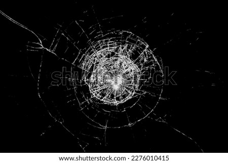 Glass broken by an impact, with black background.