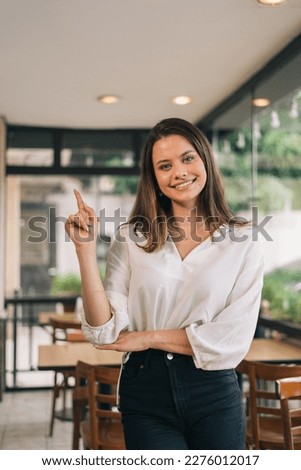 Vertical portrait with a photographic space of charming, pretty, elegant, brunette, fashionable woman in modern style shirt, pointing her finger at the empty place Royalty-Free Stock Photo #2276012017