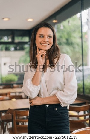 Image of an attractive young woman looking to the side posing with her hand on her face and arms crossed in a white shirt. Formal Woman Concept