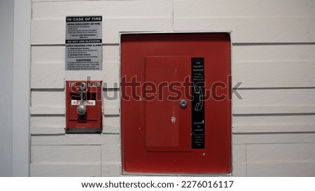 Manual pull station and communication station attached to office wall for emergency fire event