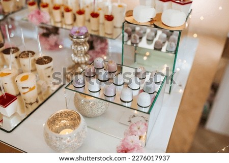 Delicious wedding reception candy bar dessert table full with cakes and sweets and flowers Chinese cherry blossoms on the background of an exquisite restaurant