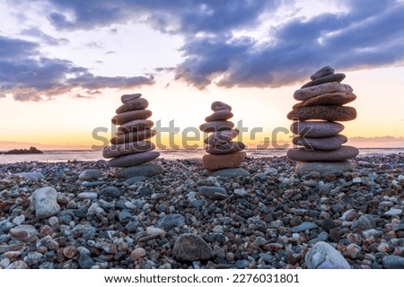 three towewrs or turrets of stone in a nice empty sea beach with coast line guring sunset or sunrise with amazing cloude sky on baclground