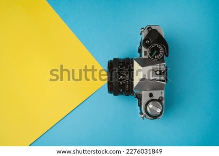 High angle view of retro film camera shooting. Film photography concept. Blue and yellow background