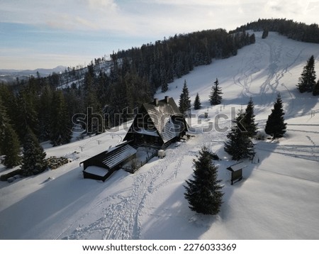 Mountain hut against the backdrop of snow-covered mountains. Mountain shelter on Rycerzowa Wielka. Beskid Zywiecki, Poland. Polish mountains in winter with the blue sky and clouds.