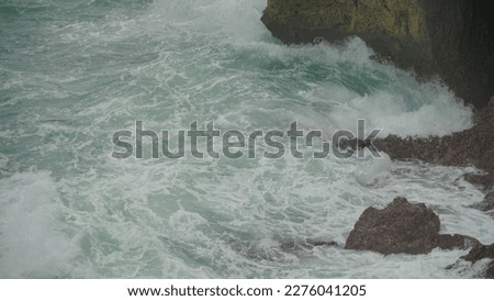 Close up shot of Ocean waves crashing against the rocks on the beach
