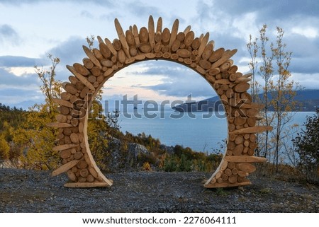 Wooden arch at the observation deck. Evening view of the sea. In the distance is a cape and rocks in the sea. Ecological tourism and nature travel. Gertner Bay, Sea of Okhotsk, Magadan region, Russia. Royalty-Free Stock Photo #2276064111