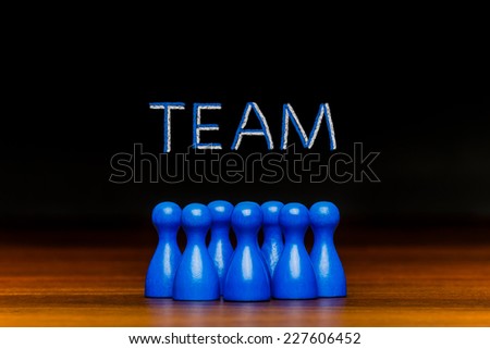 Text in chalk. Concept for: team, teamwork, collaboration, working together, group,  friends on black background. With blue pawn figures.