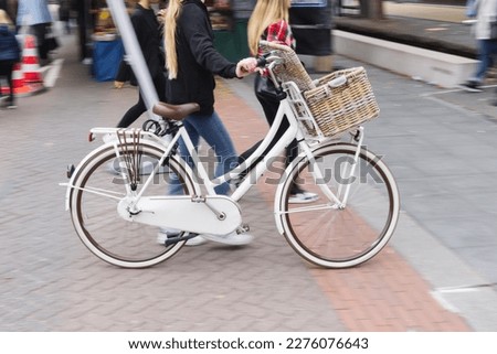 picture with camera made motion blur effect of a woman pushing a roadster bicycle in the city