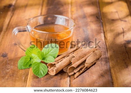 Cinnamon tea in glass cup, on wooden surface, royalty free
