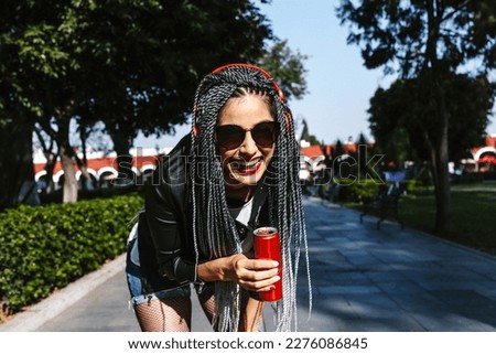 Young latin woman with braids hair holding beverage drink soda can on the street in Mexico, hispanic people Royalty-Free Stock Photo #2276086845