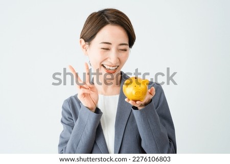 Business image of a young woman holding a piggy bank and making a peace sign
