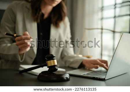 Lawyer sitting in the dark and working with laptop and report paper Justice lawyers having working on his desk,at law firm in blurred background. Royalty-Free Stock Photo #2276113135
