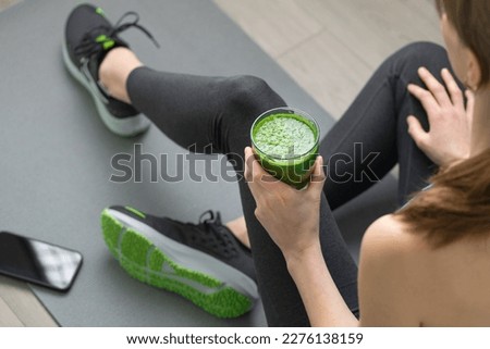 Women's hands tying sport shoes on a gray workout mat. With smoothie for detox in background. Healthy living, dieting lifestyle. Royalty-Free Stock Photo #2276138159