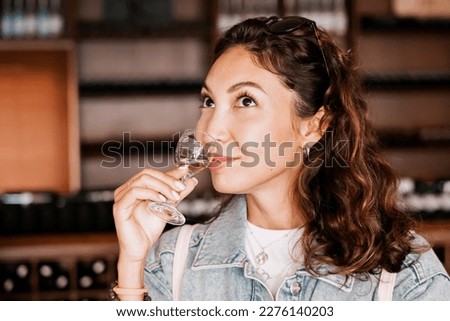 A beautiful woman takes a moment to savor the taste of a white wine sample in a winery, her glowing in delight. Royalty-Free Stock Photo #2276140203