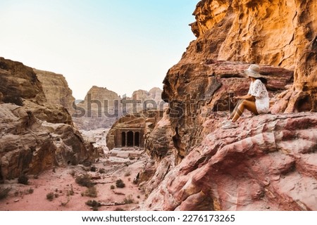 Woman traveler tourist sitting on viewpoint in Petra ancient city, ancient historical site famous travel destination of Jordan and one of seven wonders. UNESCO World Heritage site Royalty-Free Stock Photo #2276173265