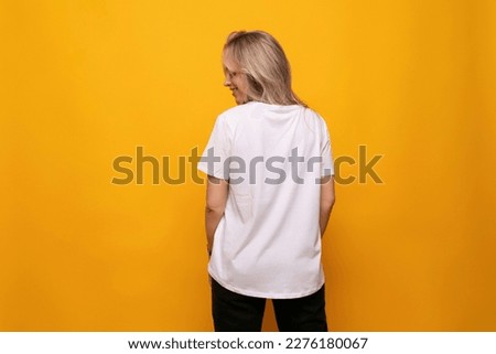a girl with a mockup of a white T-shirt stands with her back on a yellow background Royalty-Free Stock Photo #2276180067