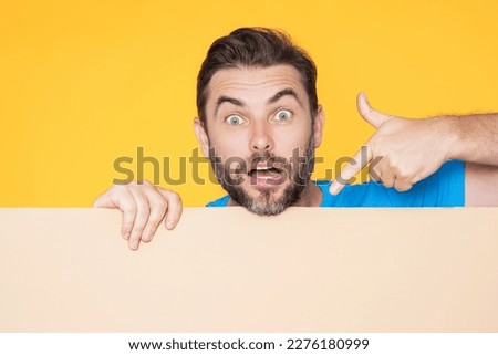 Handsome man holding empty board and pointing finger on board. Guy showing blank board with copyspace. Idea and offer. Your advertisement. Blank advertising board with empty space for text, mockup.