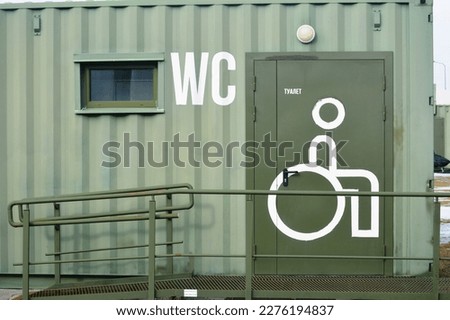 toilet sign in front of a green wall with a toilet door. The inscription on the door in Russian "toilet"