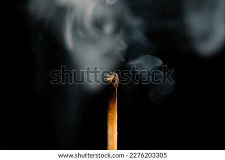 A lit match with smoke on a black background, macro photography. An extinguished match with smoke.
